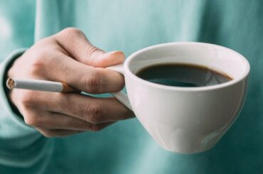 Hombre con café y cigarro en mano.