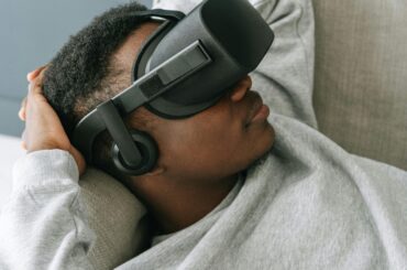 Chico tumbado en un sofa con gafas de realidad virtual.