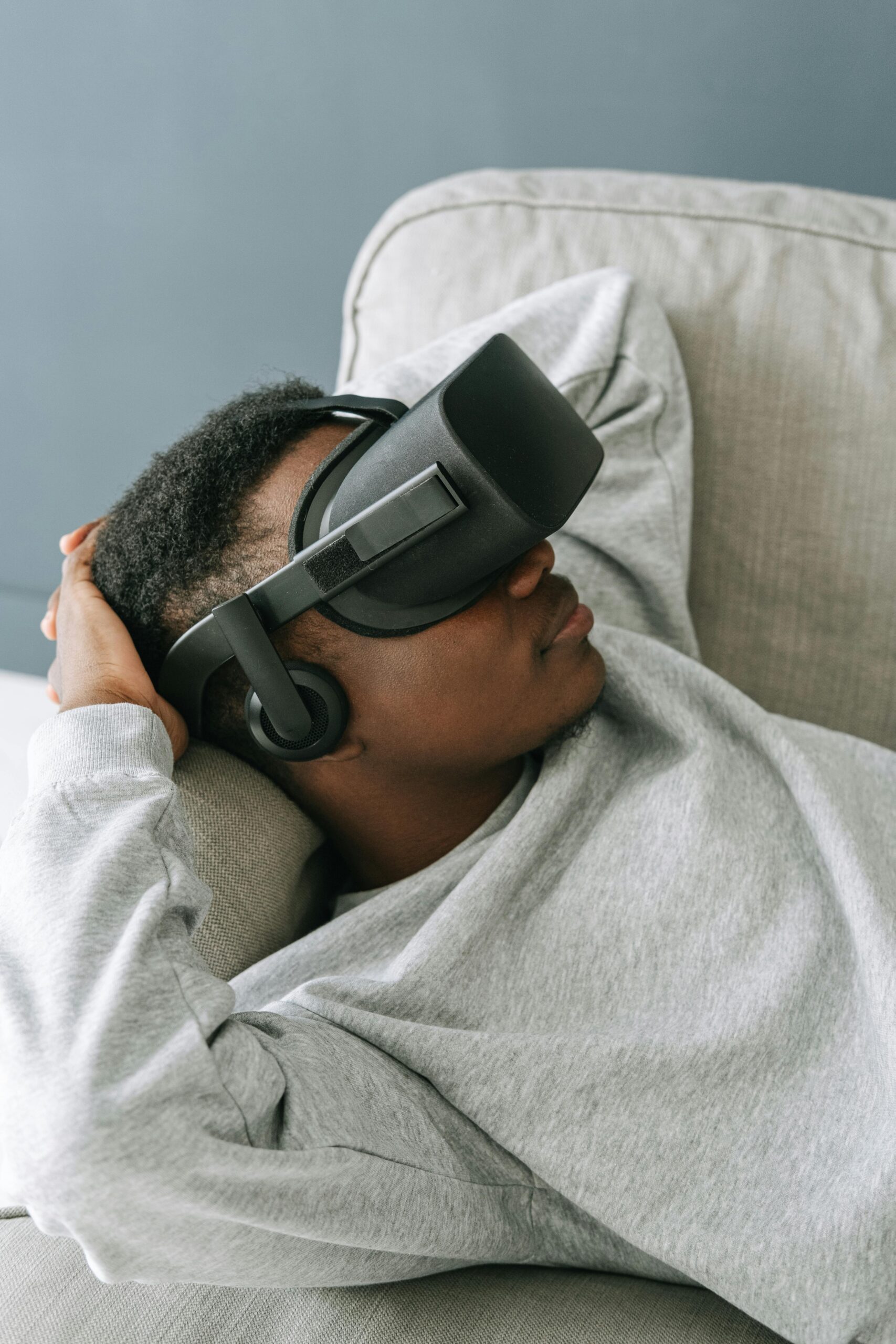 Chico tumbado en un sofa con gafas de realidad virtual.