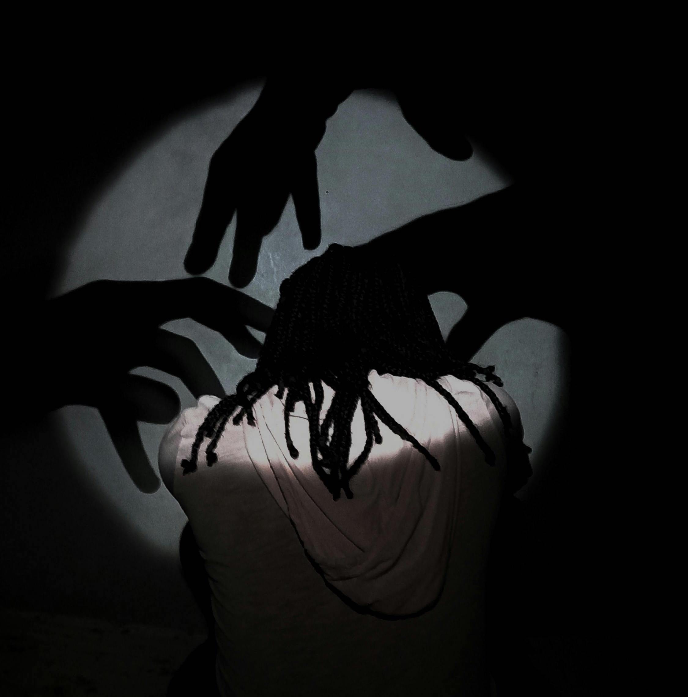 mujer siendo rodeada por sombras de manos